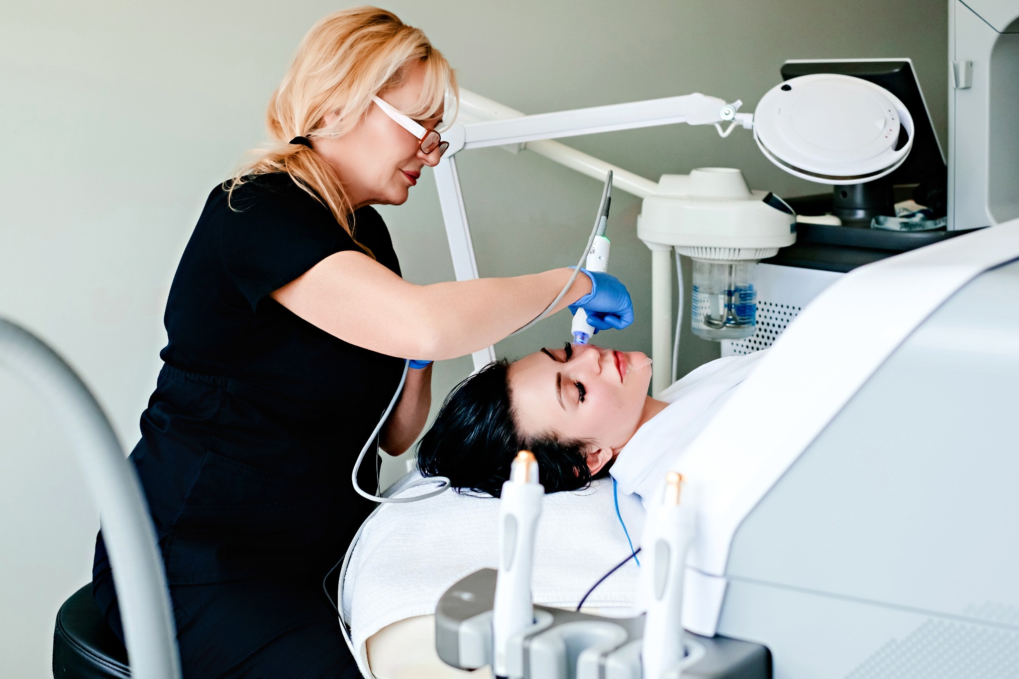 Wide view of a provider treating a patient with a facial device in a full clinical treatment room